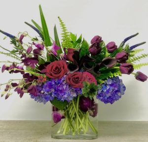 purple orchids red roses and tulips and purple and green accents in vase