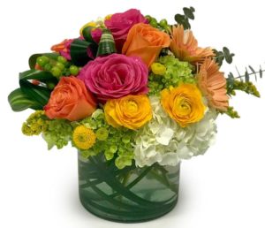 yellow ranunculas orange and pink roses with green accents in vase