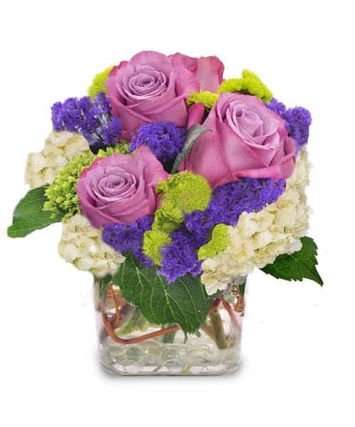 This adorable cube is filled with purple roses, hydrangea and more. This is a very petite design.