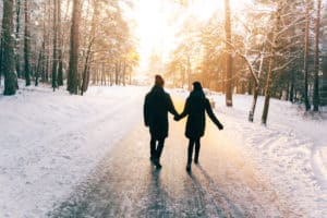 Couple holding hands walking through snow